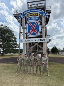Group of defenders from the 21SFS stand together in front of a rapelling tower.