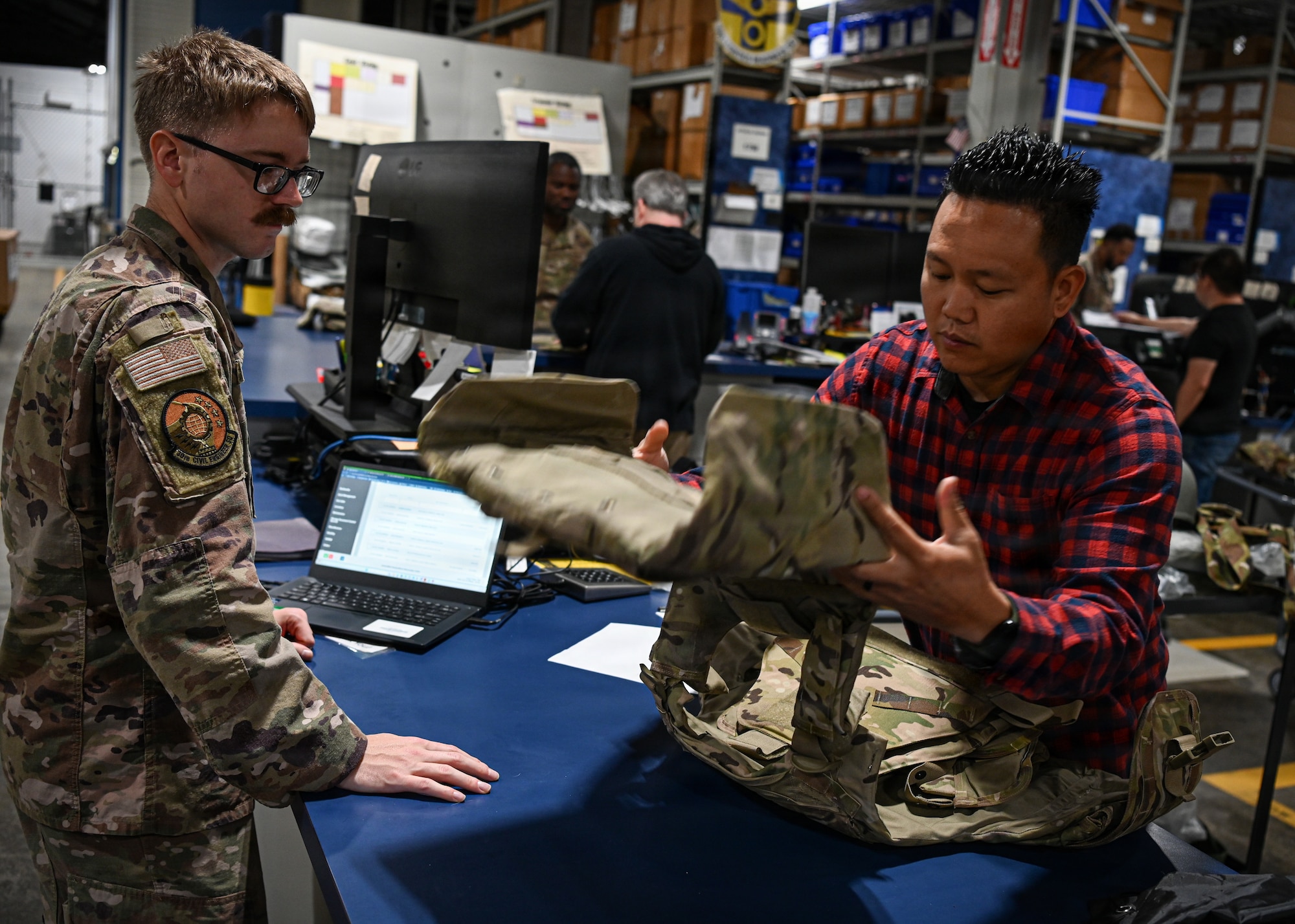 An Air Force member returns his equipment, to include his modular armored plate vest, to a member of the Vandenberg Installation Readiness Deployment Center.