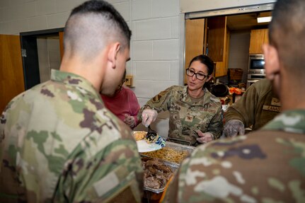 U.S. Air Force Col. Kelli R. Moon, right, commander of the 11th Operations Group, places food on the plate of an Airman during a Thanksgiving lunch at Joint Base Anacostia-Bolling, Washington, D.C., Nov. 26, 2025. JBAB commanders, first sergeants and superintendents served a Thanksgiving meal, focused on single service members, to bond over their unity and shared purpose to the nation. (U.S. Air Force photo by Hayden Hallman)