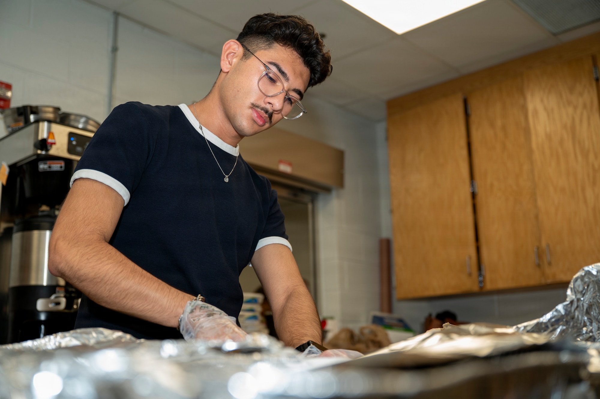 Airman Nicholas Peña, a network technician with the 690th Intelligence Support Squadron, prepares food during a Thanksgiving lunch at Joint Base Anacostia-Bolling, Washington, D.C., Nov. 26, 2025. Peña volunteered to serve hot meals to Airmen and Guardians who were unable to go home for the holiday. He is also planning to host a “Friendsgiving” in the dormitory on Thanksgiving stemming from his desire to care for his fellow dorm residents. (U.S. Air Force photo by Hayden Hallman)