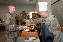 U.S. Air Force Col. James M. Clark, right, commander of Joint Base Anacostia Bolling and the 11th Wing, places food on the plate of Airman Emil Didenko-Gamart, left, a U.S. Air Force Honor Guard technical school trainee, during a Thanksgiving lunch at Joint Base Anacostia-Bolling, Washington, D.C., Nov. 26, 2025. The 11th Wing hosted the event at the JBAB Chapel to thank single service members for their hard work, sacrifices and dedication to the mission throughout the year. (U.S. Air Force photo by Hayden Hallman)