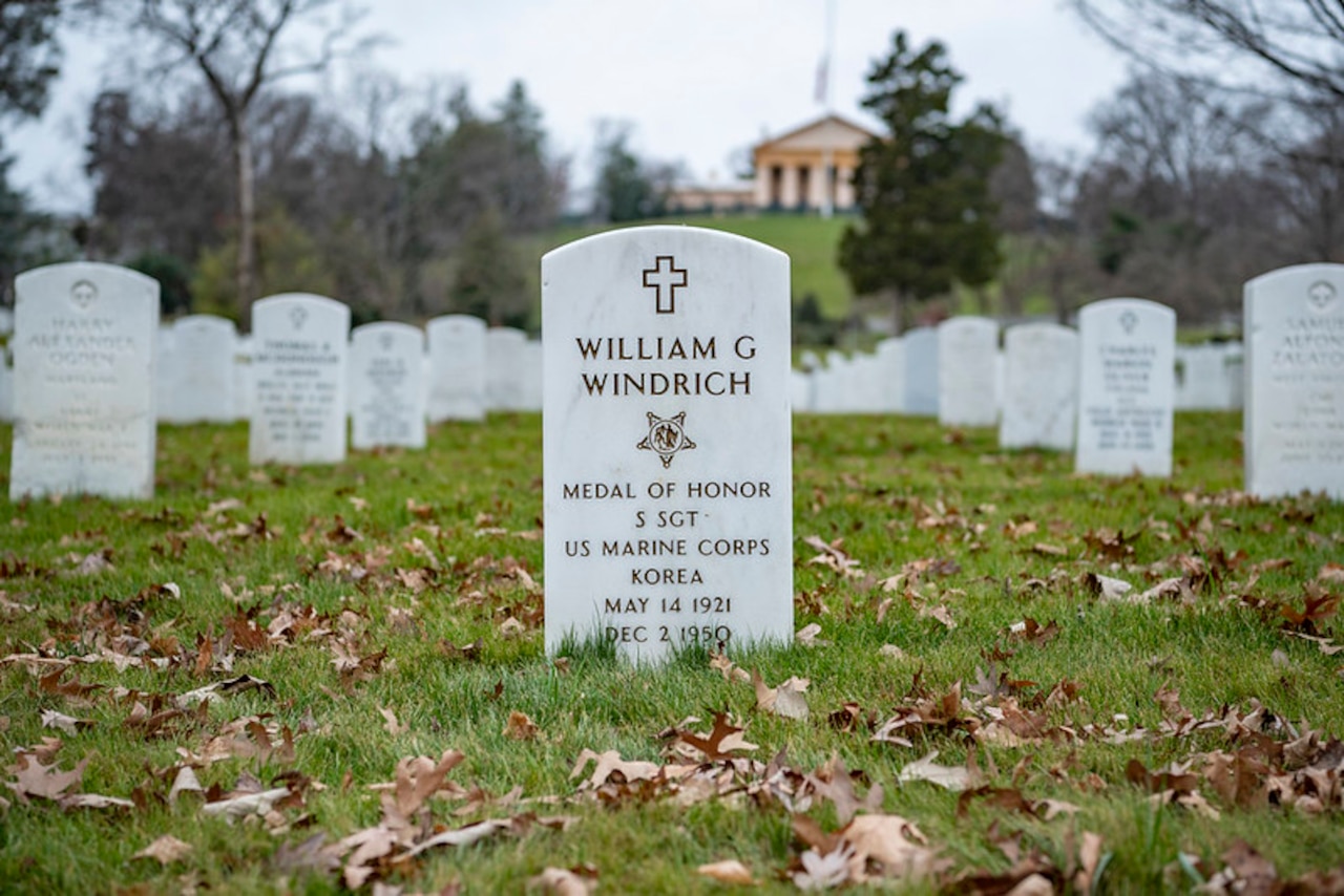 A grave marker is highlighted prominently among a field of other matching grave markers.