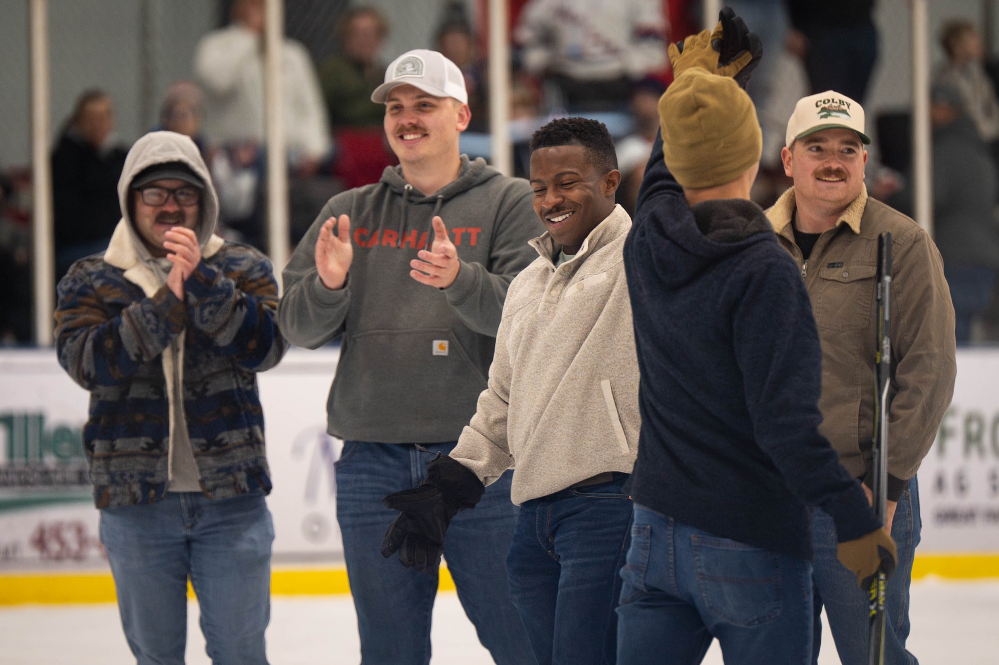 Men in civilian attire clap and high five each other.