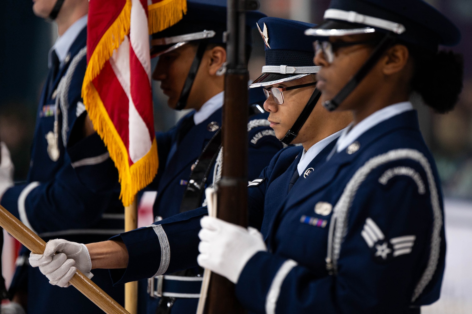 Uniformed personnel hold flags and rifles.