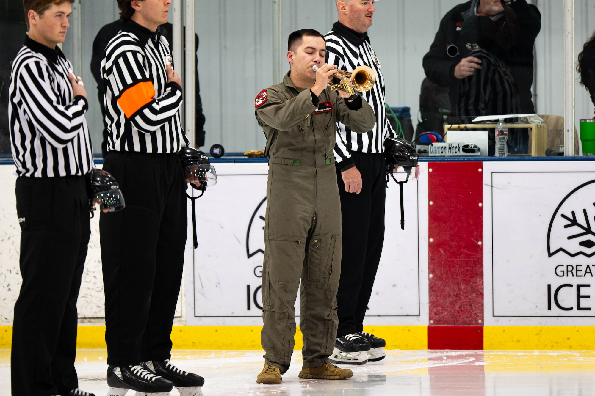 A man in uniform plays the national anthem on a trumpet.