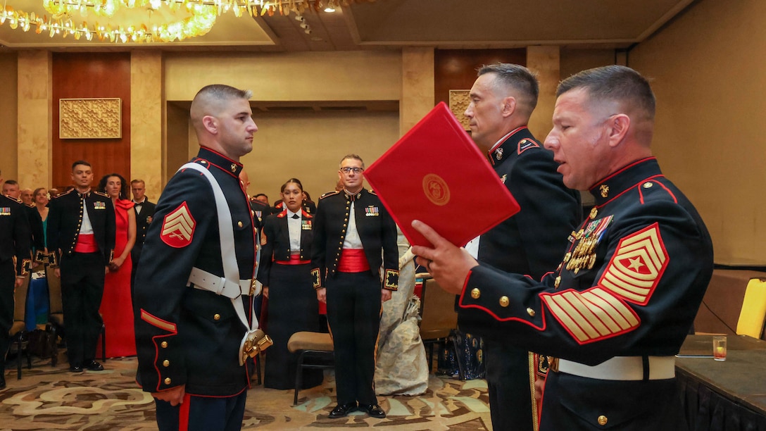 U.S. Marine Corps Sgt. Maj. Christopher Rivera, right, command senior enlisted leader, reads the Navy and Marine Corps Achievement Medal citation for Sgt. Michael Beers, network administrator, both with Marine Aircraft Group 24, 1st Marine Aircraft Wing, during the MAG-24 birthday ball celebration at the Hilton Hawaiian Village Resort, Honolulu, Hawaii, Nov. 15, 2025. Founded on November 10, 1775, the United States Marine Corps has served our nation honorably in every clime and place for 250 years. Throughout 2025, Marines across the globe will celebrate the 250th birthday of the Corps commemorating service, sacrifice, and priding themselves on living “Semper Fidelis” or “Always Faithful” to their nation and to each other. (U.S. Marine Corps photo by Lance Cpl. Roger-Junior Annoh)