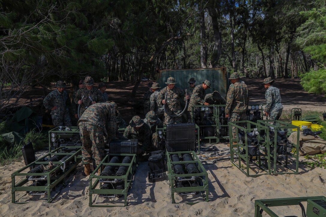 U.S. Marines with Marine Wing Support Squadron 174, Marine Aircraft Group 24, 1st Marine Aircraft Wing, attach a discharge hose at Marine Corps Training Area Bellows, Waimanalo, Hawaii, Oct. 15, 2025. The purpose of this training was to increase proficiency using the Tactical Water Purification System to push water into the Water Storage and Distribution System pumps. (U.S. Marine Corps photo by Lance Cpl. Chandler Evans)
