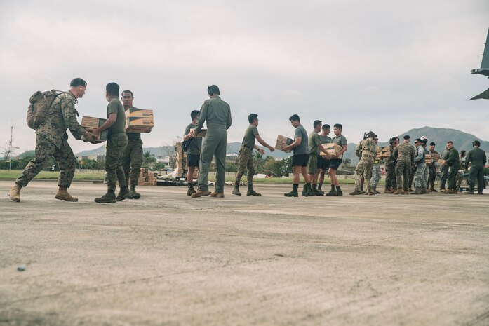 U.S. Marines with the 15th Marine Expeditionary Unit, I Marine Expeditionary Force; U.S. Airforce Airmen with 374th Airlift Wing; and Armed Forces of the Philippines service members deliver hundreds of family food packs in support of foreign disaster relief operations at Virac, Philippines, Nov. 15, 2025.