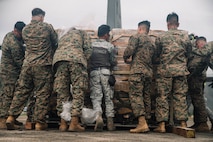 Philippine Air Force Airman 2nd Class Renz Dumanan, center, a supply specialist assigned to Tactical Operations Group 5, is joined by U.S. Marines assigned to the 15th Marine Expeditionary Unit, I Marine Expeditionary Force, and Marine Medium Tiltrotor Squadron (VMM) 262, Marine Aircraft Group 36, 1st Marine Aircraft Wing, as they offload hundreds of family food packs in support of foreign disaster relief operations at Virac, Philippines, Nov. 15, 2025.