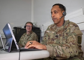 U.S. Army Col. Haileyesus Bairu, Commander of the 52nd Air Defense Artillery Brigade, listens to a Fires Support Element update brief in support of simulated V Corps operations with senior enlisted leader Paul Kenneth, left, Command Sgt. Maj. of the 52nd Air Defense Artillery Brigade, during Avenger Triad 25, Oct. 30, 2025, Camp Kosciuszko, Poland.