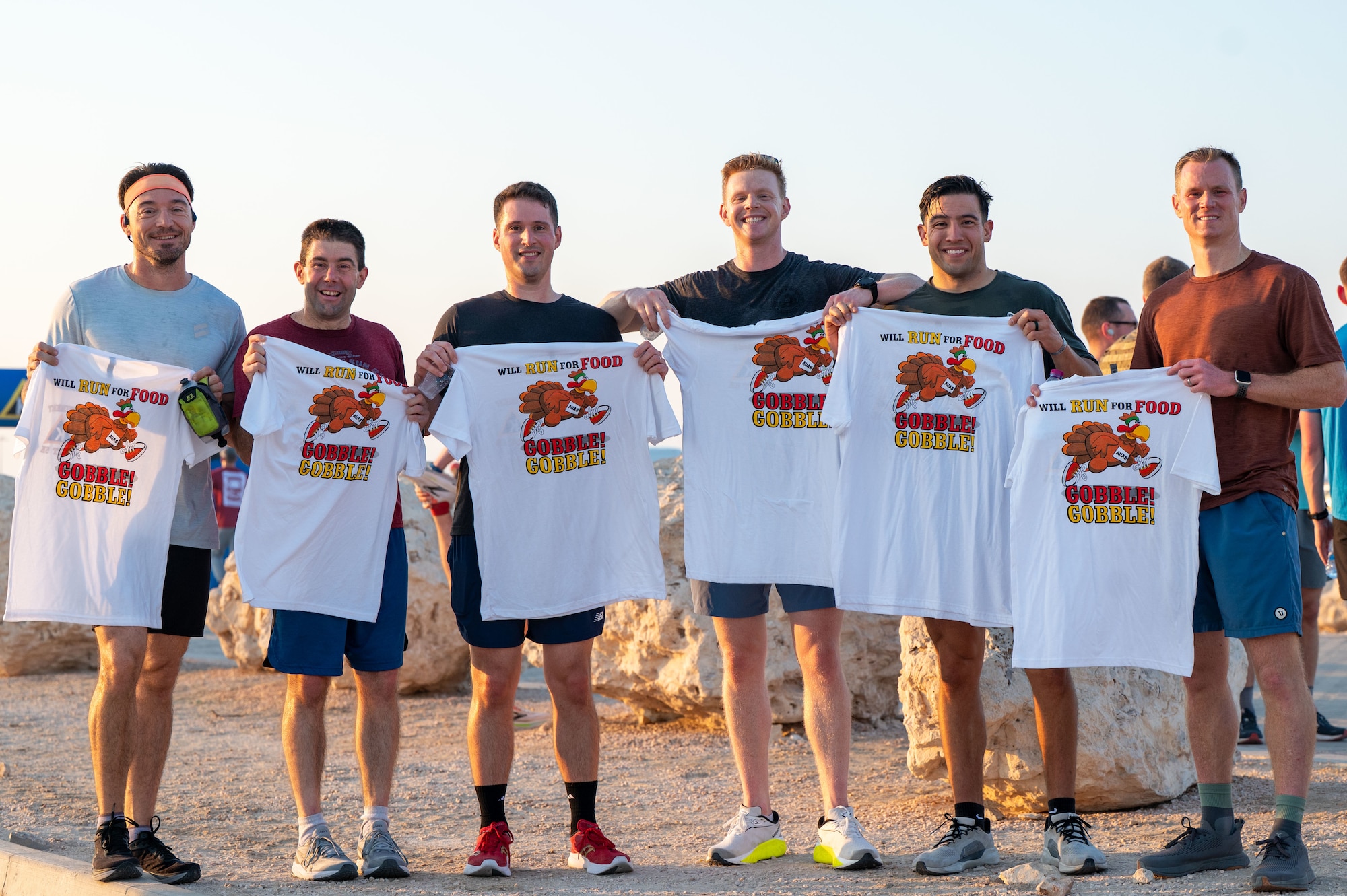 Six men lineup holding t-shirts that say "Will run for food" and "Gobble! Gobble!"