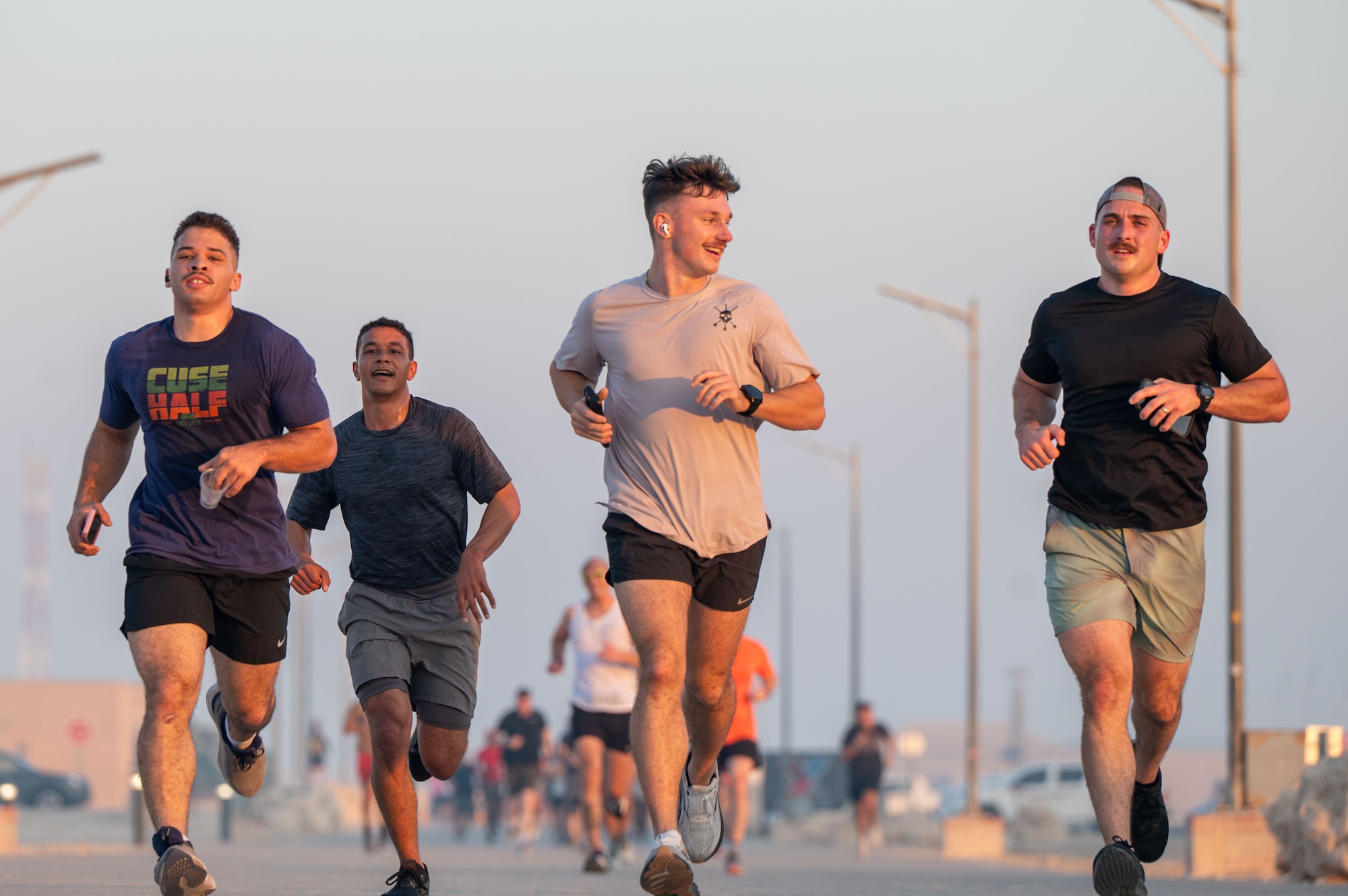 Four men run while others can be seen out of focus in the distant background