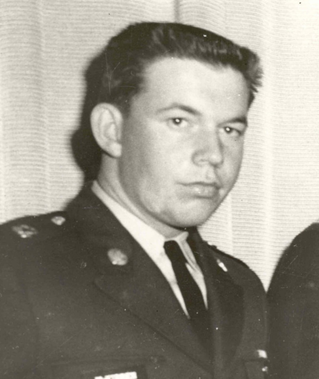 A man in a military dress uniform looks stoic for a photo.