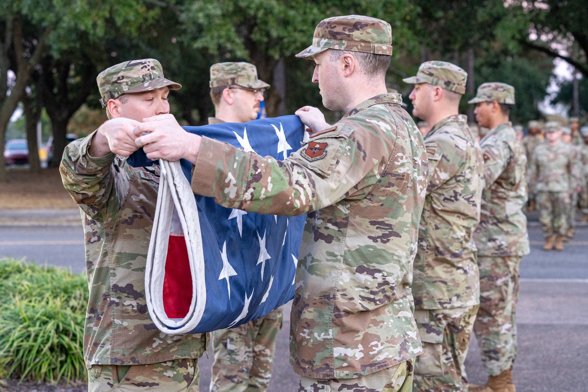 Six servicemen in OCPs folding a flag.
