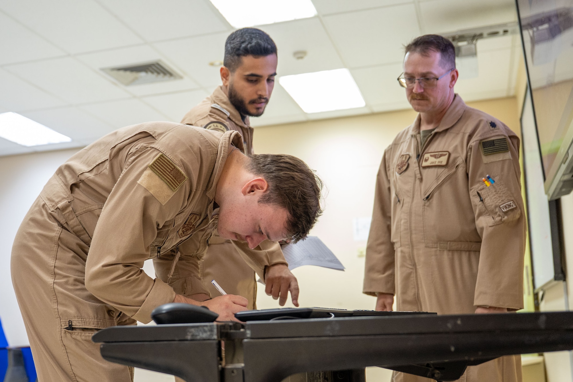 Center, a Royal Saudi Air Force service member completes a flight manifest with U.S. Air Force Senior Airman Michael Gucherless, 960th Expeditionary Airborne Air Control Squadron airborne radar technician, left, and Lt. Col. Jacob Ivie, 960th EAACS commander, right, before an integrated E-3 Sentry sortie.