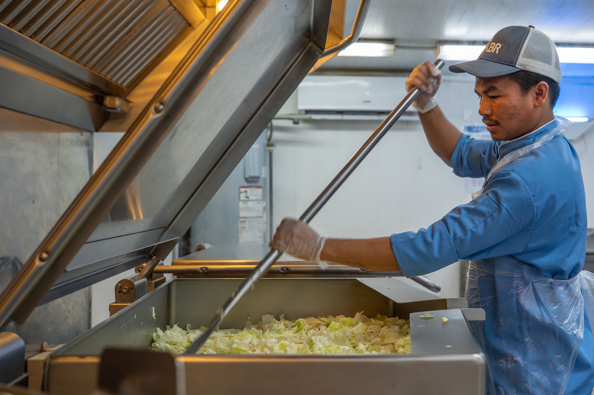 Dunpu Sherpa, a Kellogg, Brown, and Root logistics support area dining cook, prepares cabbage for the lunch meal that will serve thousands of service members.