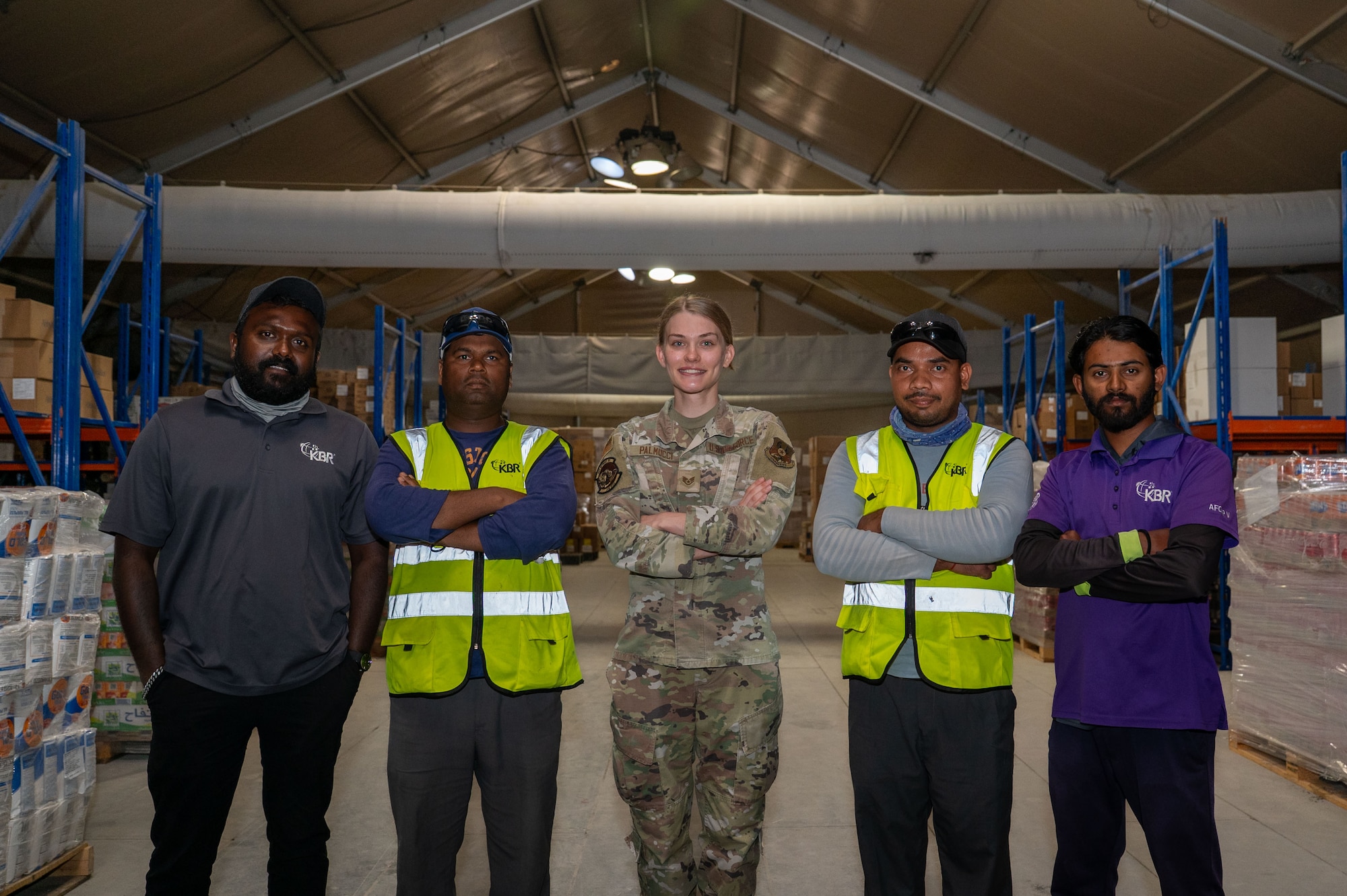Center, U.S. Air Force Tech. Sgt. Gianna Palmucci, 378th Expeditionary Force Support Squadron storeroom and accounting operations noncommissioned officer in charge, poses for a photo with Kellogg, Brown, and Root government contractors.