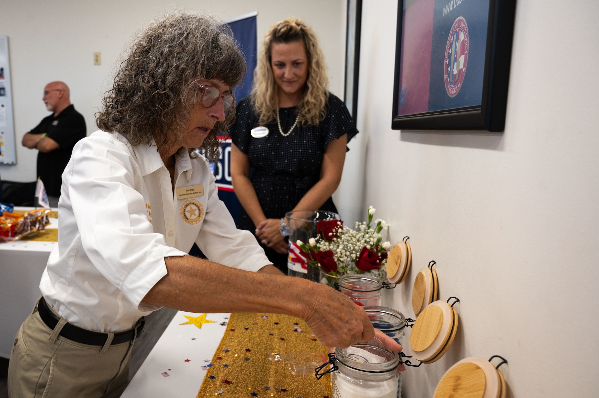 Toni Gross, Gold Star Mother of U.S. Army Corporal Frank R. Gross, fills a jar with sand during the Gold Star Mother’s and Family Day event at MacDill Air Force Base, Florida, Sept. 28, 2025. Each color of sand represents a different aspect of the fallen member’s life, red, blue, white, and gold represent values such as bravery, loyalty, peace, and honor respectively. The jars are a tribute to each fallen service member.(U.S. Air Force photo by Senior Airman Sterling Sutton)