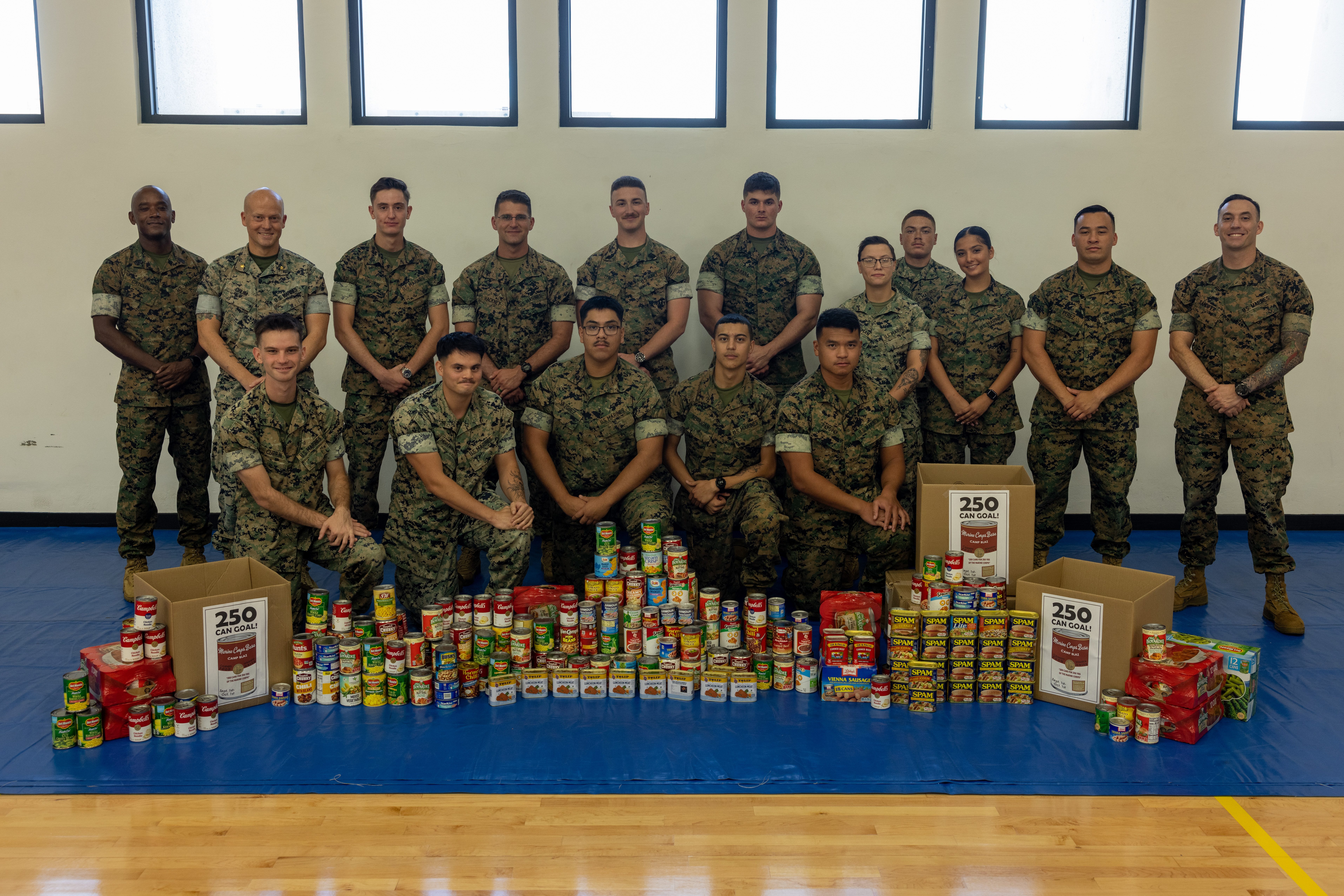 U.S. Marines pose for a photo in front of cans collected during a canned food drive held by Marine Corps Base Camp Blaz, on MCB Camp Blaz, Guam, Oct. 1, 2025. MCB Camp Blaz received more than double their original goal of 250 cans. (U.S. Marine Corps photo by Cpl. Ryan Little)