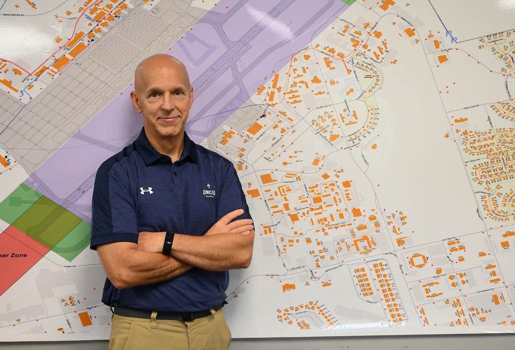 A man poses for a photo in front of a map.