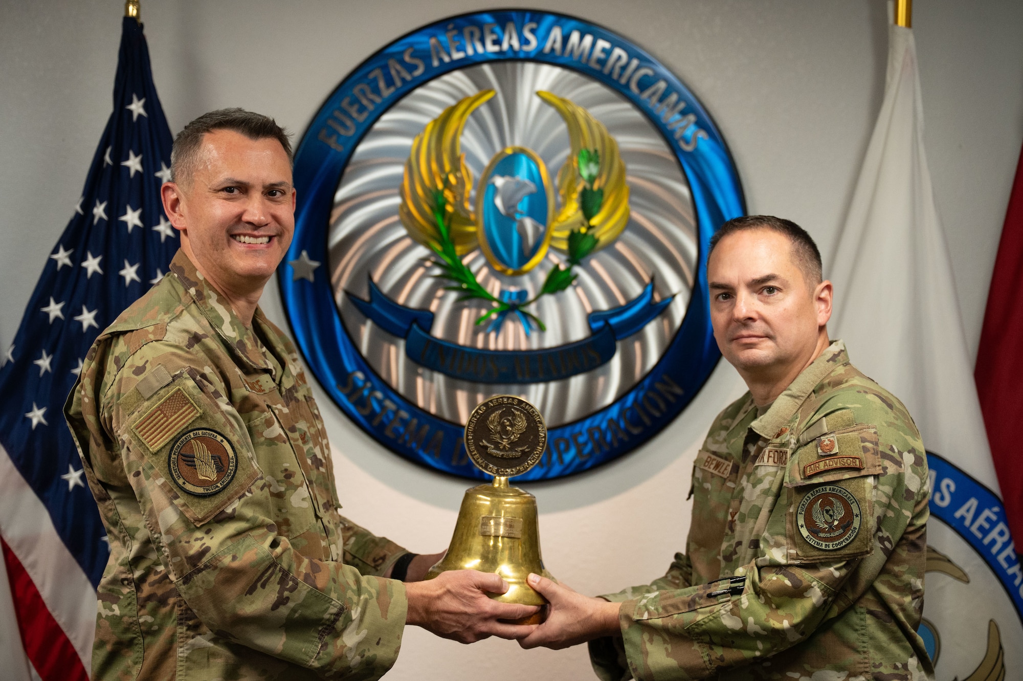 U.S. Air Force Col. David McIllece, System of Cooperation Among the American Air Forces outgoing secretary general, hands a ceremonial bell to U.S. Air Force Col. David Bewley, SICOFAA incoming secretary general, during a change of responsibility ceremony at Davis-Monthan Air Force Base, Arizona, Oct. 1, 2025. Founded in 1961, SICOFAA serves as a forum for senior leaders from air forces in the Western Hemisphere to discuss military issues and aviation topics. (U.S. Air Force photo by Airman Jaden Kidd)