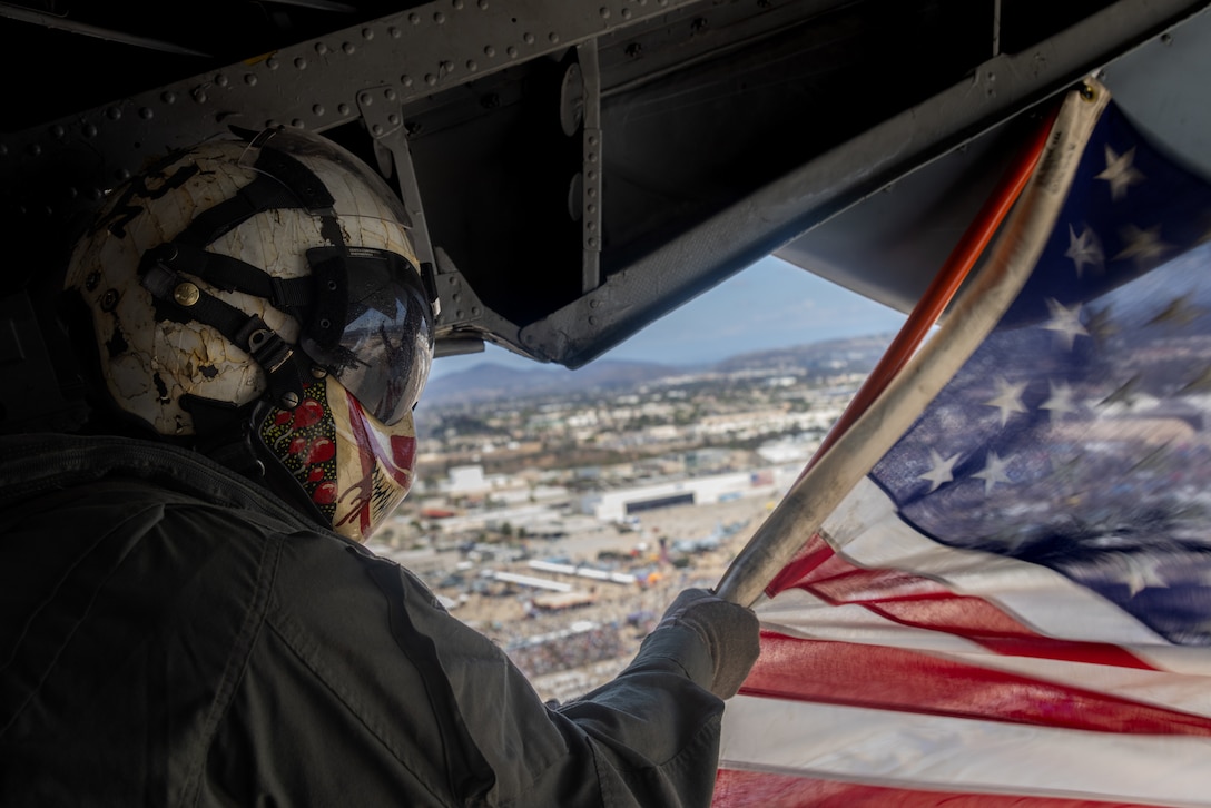 U.S. Marine Corps Gunnery Sgt. Brent Moffatt, a quality assurance chief with Marine Heavy Helicopter Squadron (HMH) 361, Marine Aircraft Group 16, 3rd Marine Aircraft Wing, waves the American flag during the Marine Air-Ground Task Force demonstration of the 2025 Marine Corps Air Station Miramar Air Show in San Diego, Sept. 28, 2025. The MAGTF Demo displays the coordinated use of close-air support, armor, artillery and infantry forces and provides a visual representation of how the Marine Corps operates. America's Air Show 2025 is a unique and incredible opportunity to witness Marine and joint aviation capabilities, civilian performers and the world-famous Blue Angels; to celebrate the 250th birthday of the Marine Corps alongside Marines and to see first-hand the innovative spirit of the Marine Corps through emerging technologies and forward-thinking. (U.S. Marine Corps photo by Lance Cpl. Jordan Searls)