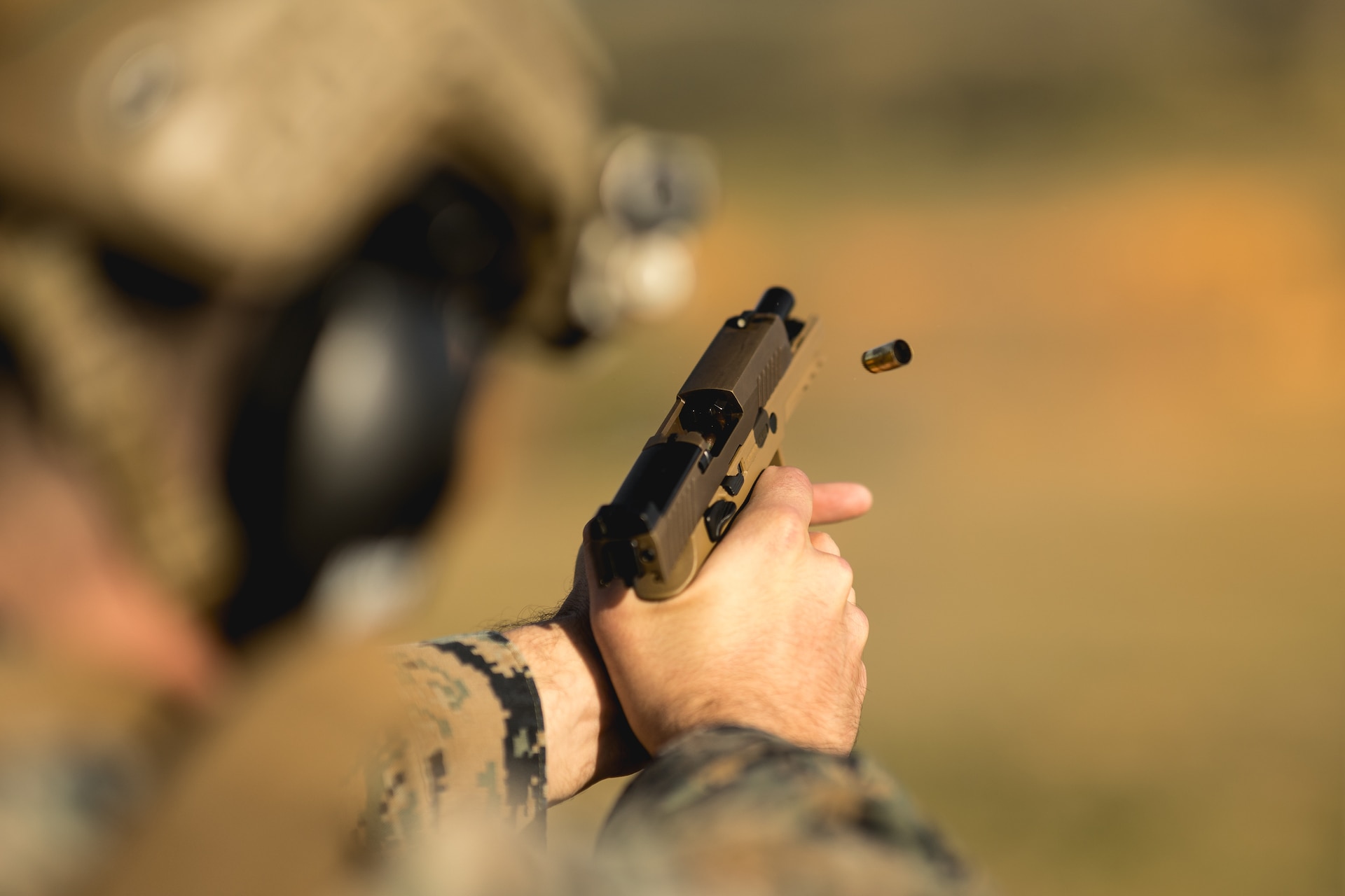 an intelligence specialist fires an M18 service pistol during a Combat Marksmanship Program range
