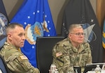 Two men in military uniform sit at a table.