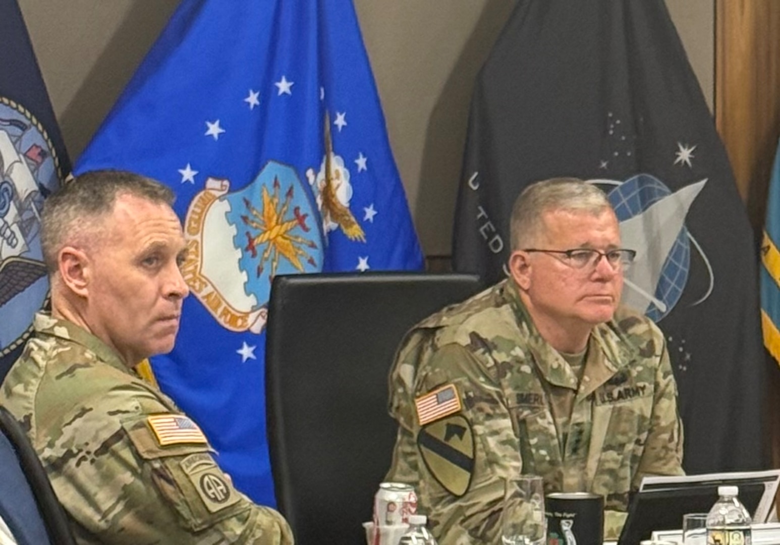 Two men in military uniform sit at a table.