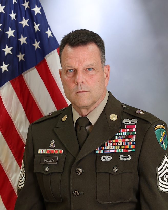 Command Sgt. Maj. Aaron A. Miller, senior enlisted advisor, 353rd Civil Affairs Command poses in front of the American flag in his Army Green Service Uniform.
