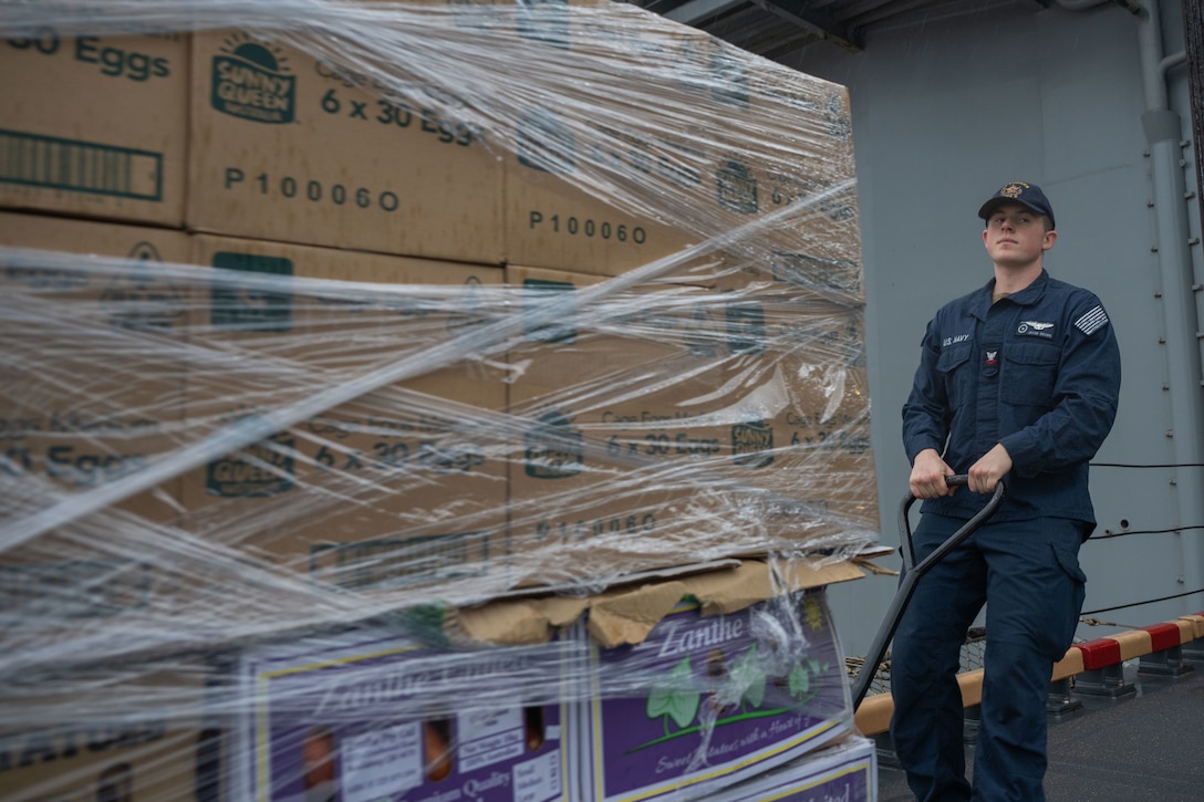 250726-N-TW227-1053 BRISBANE, Australia (July 26, 2025) Air Traffic Controller 2nd Class Jacob Brown, from Palmyra, New York, assigned to the forward-deployed amphibious assault ship USS America (LHA 6) participates in a supply onload in Brisbane, Australia, July 26