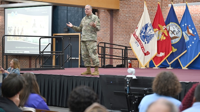 A military general stands on a stage speaking to an audience