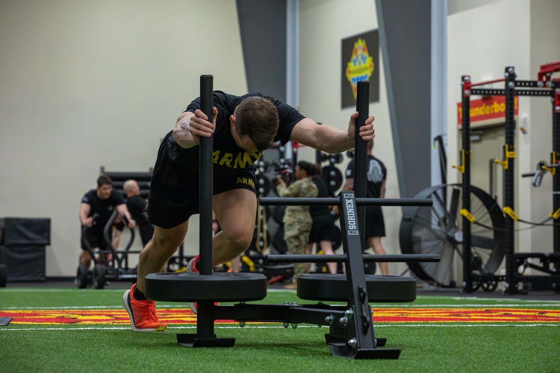 US Soldier pushes weighted sled in gym environment