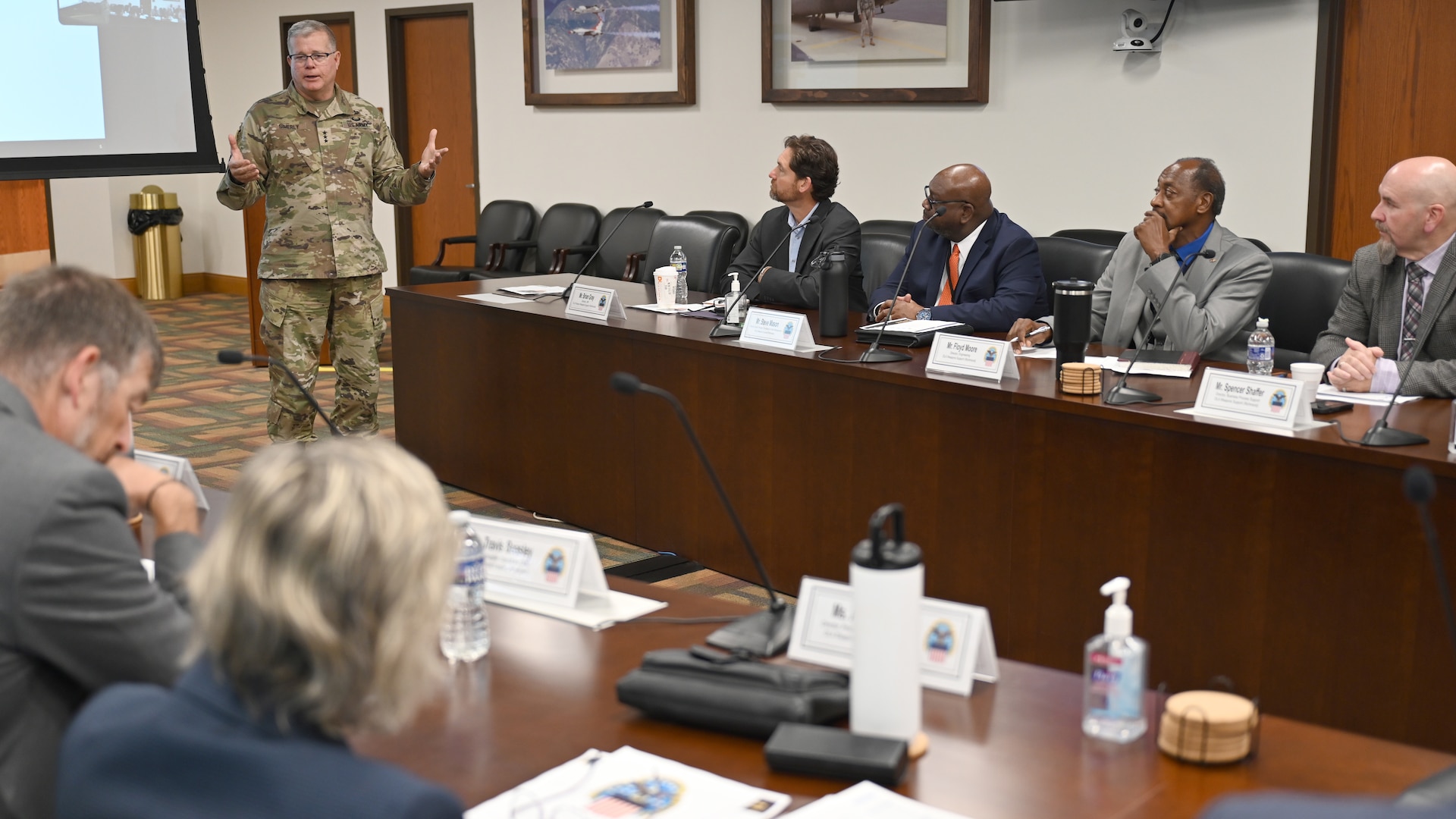 A general stands and talks to people in a conference room