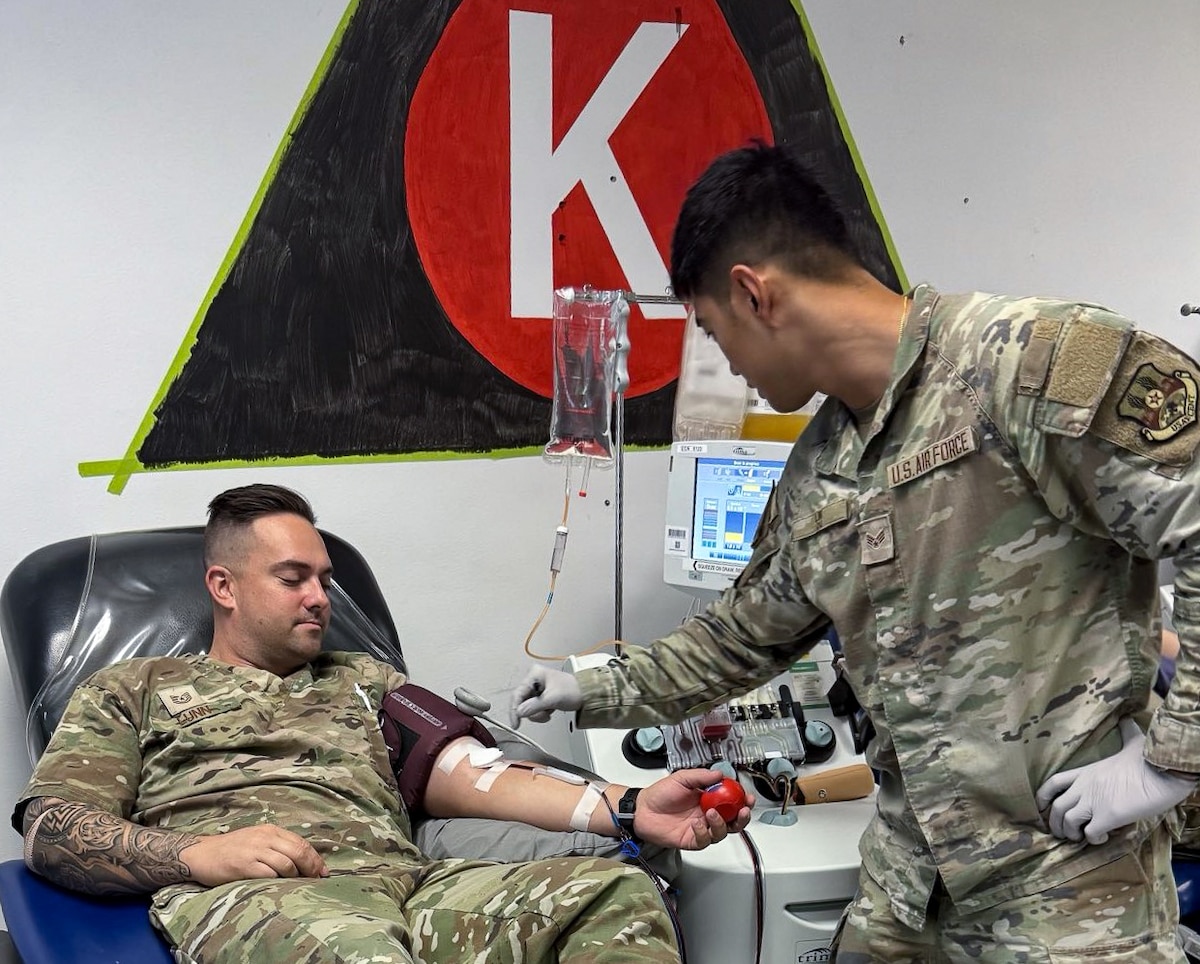 Image of one Airman donating blood and another working