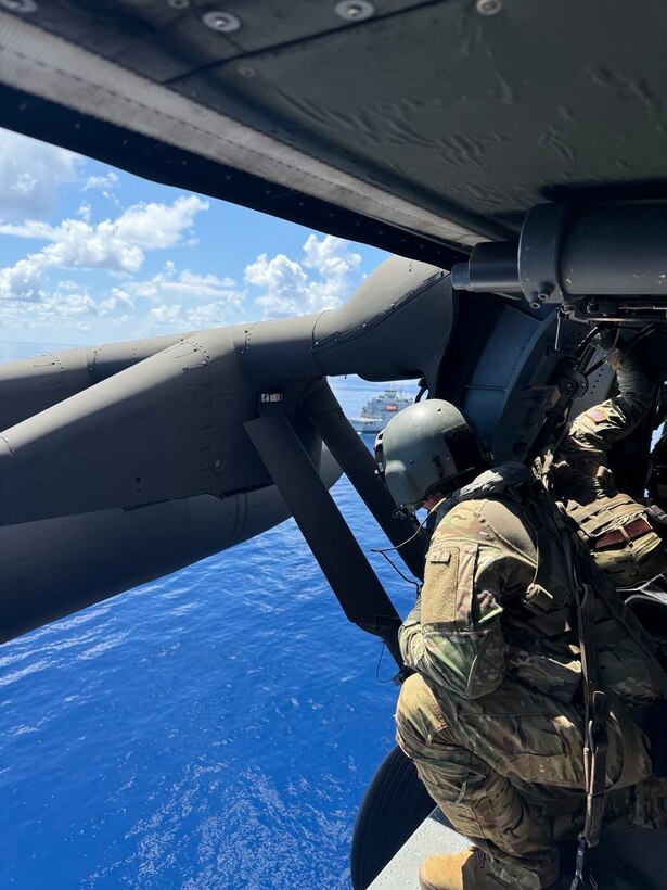 A crew member from the 1-228 Aviation Regiment spots the USNS Kennedy from the helicopter ahead of deck landing qualification training.