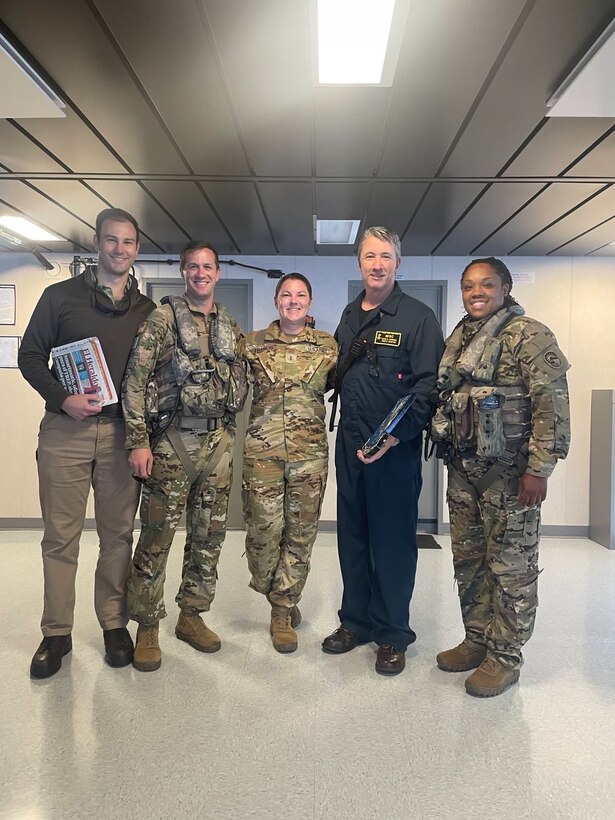 Members from the 1-228 Aviation Regiment and the USNS Robert Kennedy stand together in the control tower of the ship for a group photo following deck landing qualification training.