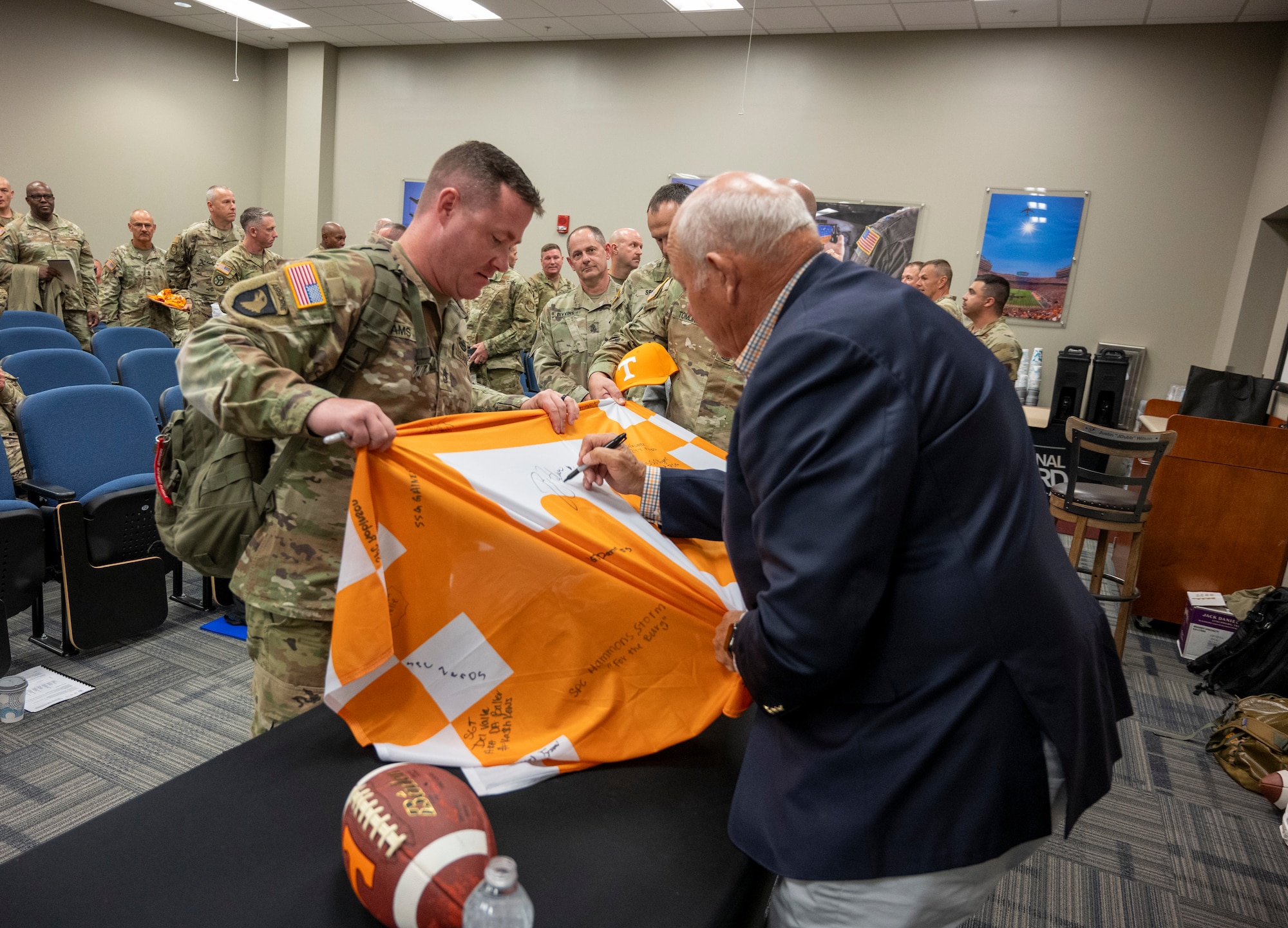 Former University of Tennessee Knoxville Athletic Director Phillip Fulmer signs a University of Tennessee flag for an Army servicemember.