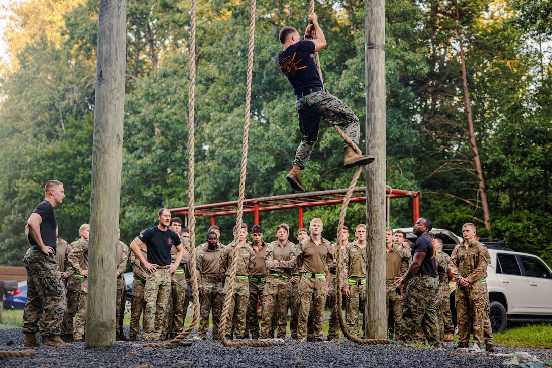 U.S. Marine Corps Gunnery Sgt. Albert Ludwig, a Force Fitness Instructor Trainer with Training Command, demonstrates obstacle course techniques to British Royal Marines as part of “Virginia Tempest” at The Basic School on Marine Corps Base Quantico, Virginia, July 28, 2025. Virginia Tempest is an annual training event where Royal Marines and U.S. Marines collaborate in training such as the obstacle course, Marine Corps Martial Arts Program, and other rigorous events, ultimately designed to support interoperability and maintaining the historic working relationship between the organizations. (U.S. Marine Corps photo by Lance Cpl. Braydon Rogers)