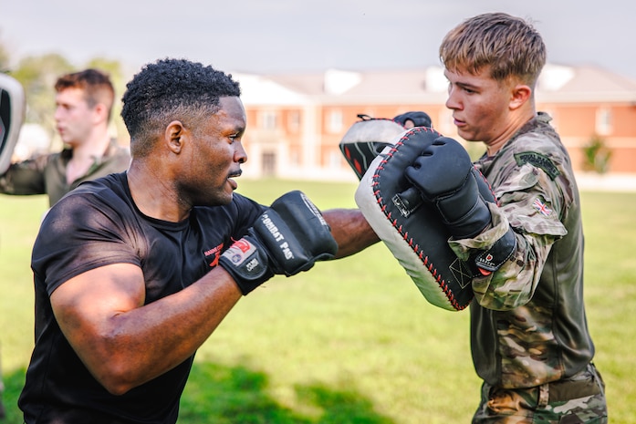 U.S. Marine Corps Staff Sgt. Frankie Cameron III, a martial arts instructor trainer with Training Command, left, and a British Royal Marine conduct hand-to-hand combat techniques during a physical training circuit as part of “Virginia Tempest” at The Basic School on Marine Corps Base Quantico, Virginia, July 30, 2025. Virginia Tempest is an annual training event where Royal Marines and U.S. Marines collaborate in training such as the obstacle course, Marine Corps Martial Arts Program, and other rigorous events, ultimately designed to support interoperability and maintaining the historic working relationship between the organizations. (U.S. Marine Corps photo by Lance Cpl. Braydon Rogers)