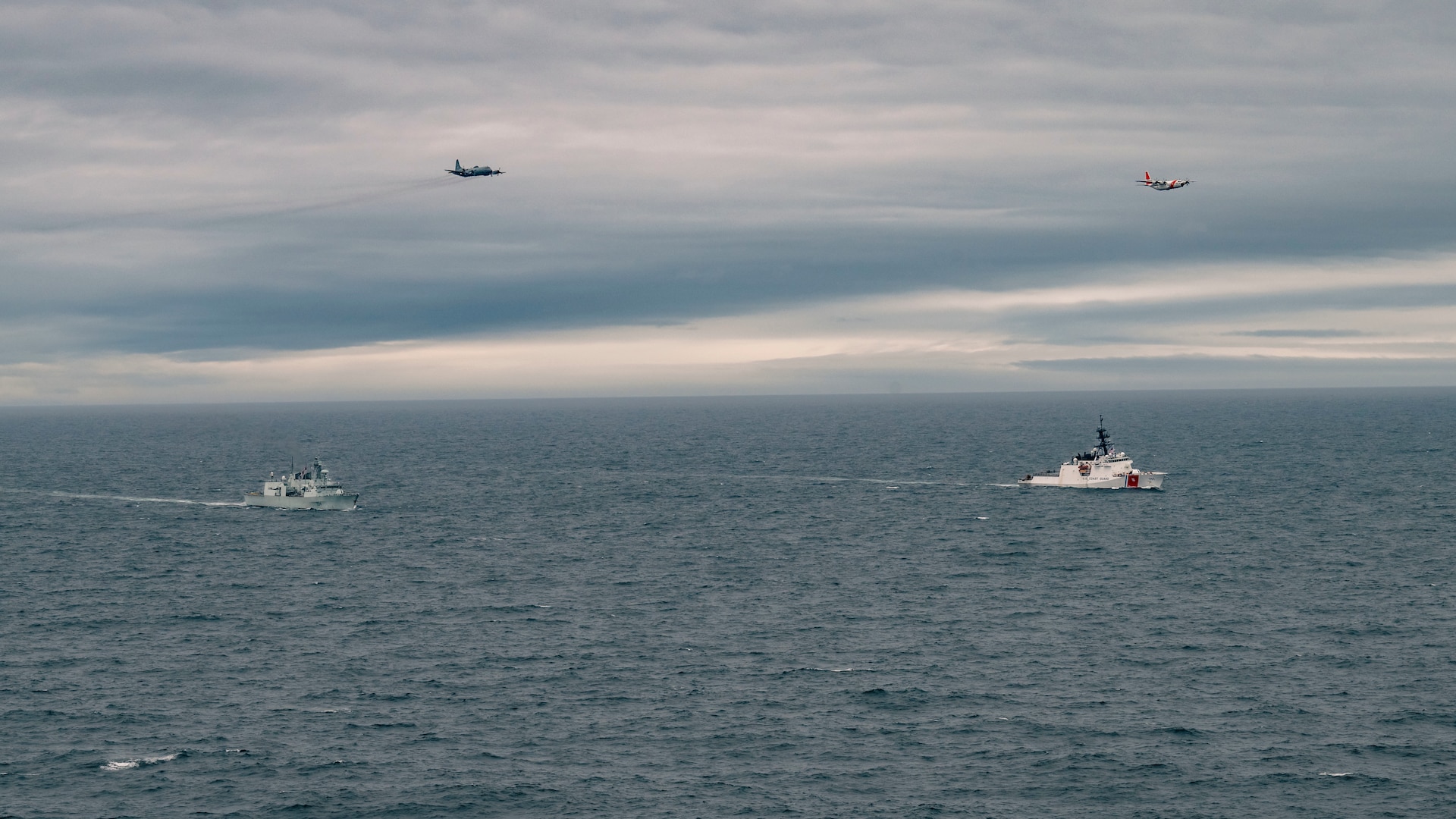 U.S. Coast Guard Cutter Waesche (WMSL-751) and Royal Canadian Navy His Majesty’s Canadian Ship Regina, sail alongside each other as a USCG Air Station Kodiak HC-130 and Royal Canadian Air Force CP-140 Aurora fly overhead during Operation LATITUDE in the Bering Sea, Alaska, Aug. 25, 2025. Canadian-led Operation LATITUDE, in conjunction with Alaskan Command and U.S. Northern Command, and U.S. Coast Guard Arctic District, focused on increasing domain awareness in the High North and enhancing interoperability between Canada and the United States. (Courtesy photo by Canadian Armed Forces Master Corporal William Gosse)