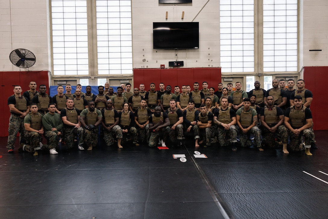 U.S. Marine Corps Martial Arts Instructors and Instructor Trainers attending the Marine Corps Martial Arts 25th anniversary symposium hosted by the Martial Arts and Fitness Center of Excellence pose for a group photo on Marine Corps Base Quantico, Virginia, Oct. 9, 2025. The goal of this symposium was to provide the Fleet Marine Force with instructions and practical application on the new tan-black belt syllabus and the new free sparring events while integrating guided discussions fostering character development and recounting the storied tradition of the Marine Corps Martial Arts Program. (U.S. Marine Corps photo by Cpl. Joshua Barker)