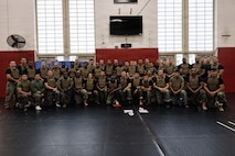 U.S. Marine Corps Martial Arts Instructors and Instructor Trainers attending the Marine Corps Martial Arts 25th anniversary symposium hosted by the Martial Arts and Fitness Center of Excellence pose for a group photo on Marine Corps Base Quantico, Virginia, Oct. 9, 2025. The goal of this symposium was to provide the Fleet Marine Force with instructions and practical application on the new tan-black belt syllabus and the new free sparring events while integrating guided discussions fostering character development and recounting the storied tradition of the Marine Corps Martial Arts Program. (U.S. Marine Corps photo by Cpl. Joshua Barker)