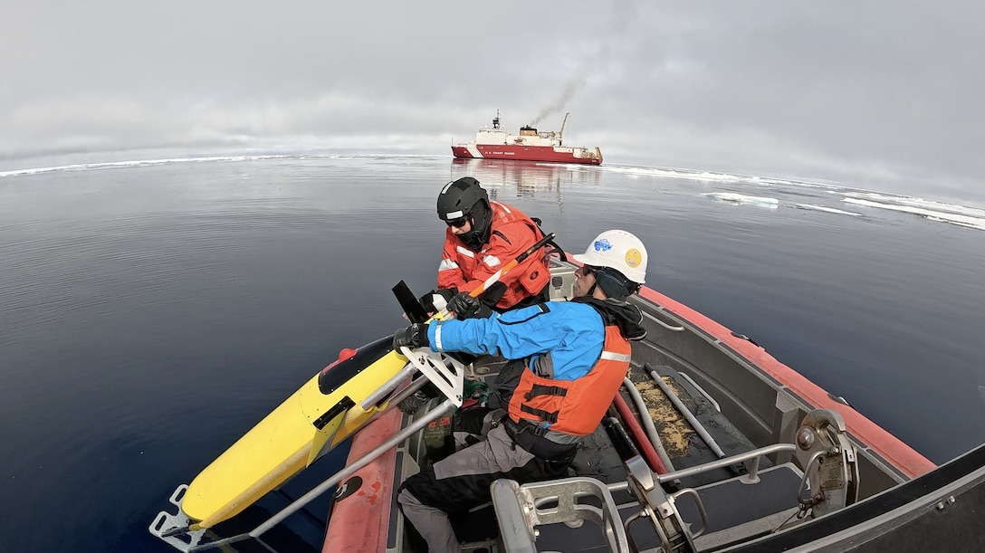 U.S. Coast Guard Petty Officer 2nd Class Jared Vannoy (right) and Justin Burnett, an Arctic Mobile Observing System research engineer, pull a Seaglider Undersea Vehicle aboard a Coast Guard Cutter Healy (WAGB 20) small boat while operating in the Arctic Ocean, Aug. 5, 2025. The dense batteries in the seaglider are mounted on a rail to allow adjustments to its center of gravity, creating the ability to steer. (U.S. Coast Guard courtesy photo by Petty Officer 2nd Class Zack Ledoux)