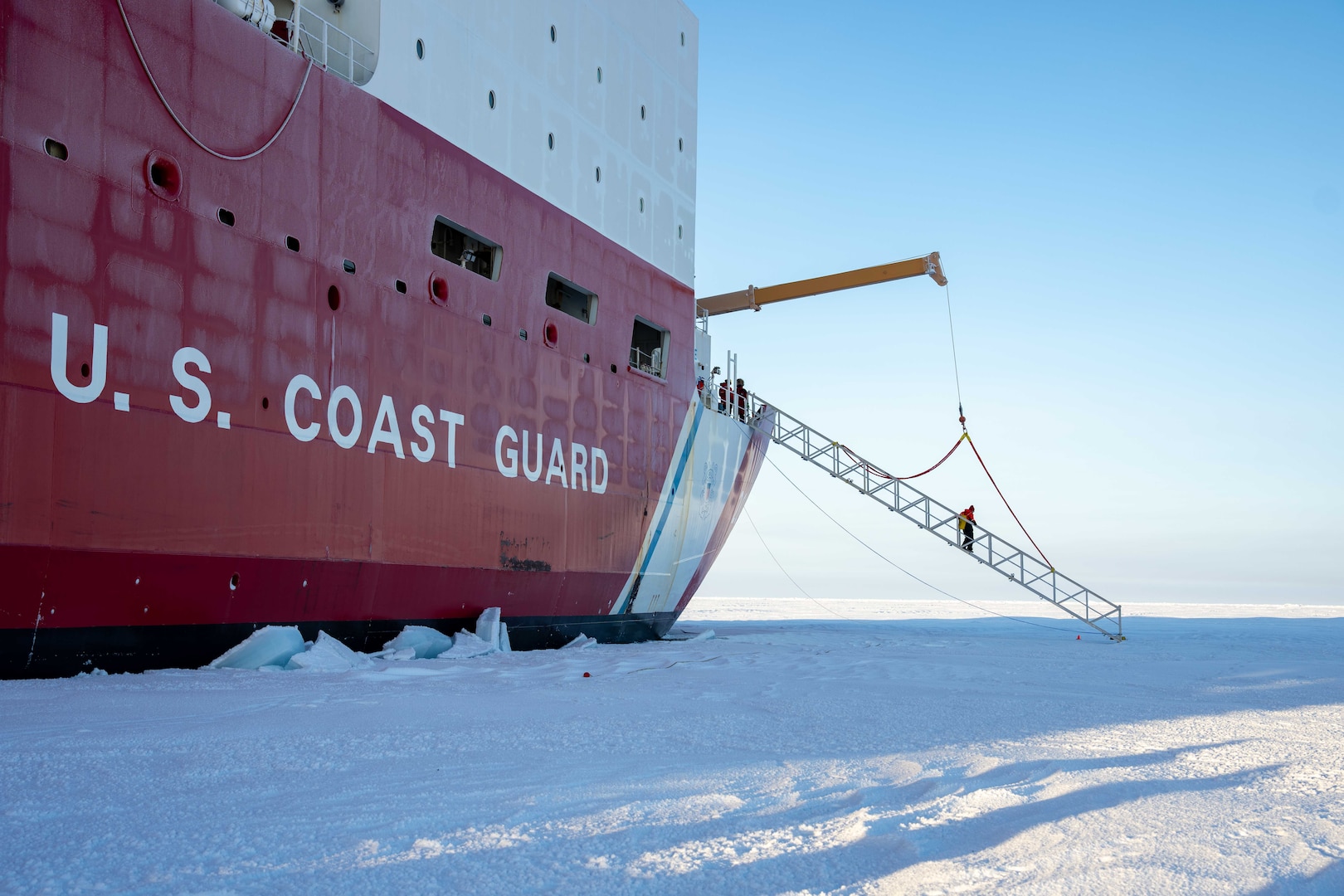 A U.S. Coast Guard Cutter Healy (WAGB 20) crewmember crosses the brow onto the ice while operating in the Arctic Ocean, Oct. 1, 2025. Coast Guard operations in the Arctic are critical to expanding our understanding of the Arctic operating environment for advancing national security objectives. (U.S. Coast Guard photo by Petty Officer 3rd Class Chris Sappey)