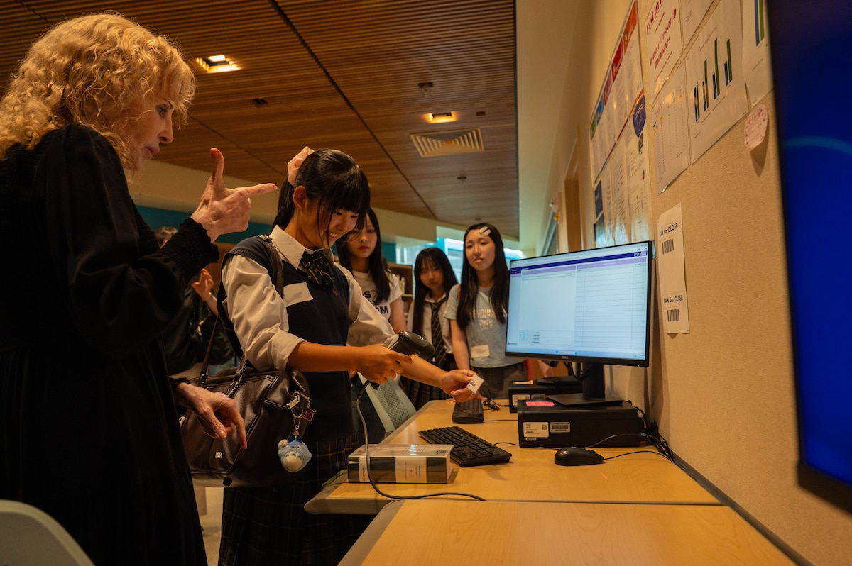 A teacher helps a student with a computer.