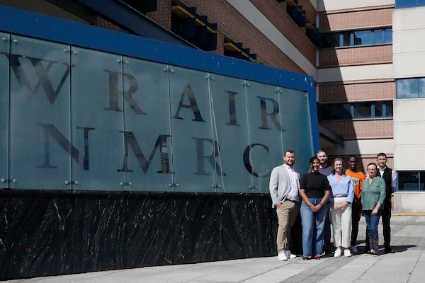 SILVER SPRING, Md. (Aug. 25, 2025) Staff with Naval Medical Research Command (NMRC) and Walter Reed Army Institute of Research (WRAIR) pose for a group photo outside the Robert K. Inouye building at Forest Glen Annex. Scientists from NMRC and WRAIR are collaborating to develop an antimicrobial therapy to treat commonly drug-resistant bacteria. This research has allowed scientists from both organizations to band together and test the effectiveness of multiple versions of the therapy. Developing an antibiotic alternative that is easily accessible will allow service members to have better resources in environments where traditional healthcare is not available.  NMRC, headquarters of Navy Medicine Research & Development, is engaged in a broad spectrum of activity from basic science in the laboratory to field studies in austere and remote areas of the world to investigations in operational environments. In support of Navy, Marine Corps and joint U.S. warfighter health, readiness and lethality, researchers study infectious diseases, biological warfare detection and defense, combat casualty care, environmental health concerns, aerospace and undersea medicine, operational mission support and epidemiology. (U.S. Navy photo by Aleece Williams/Released)
