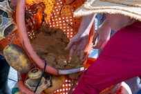Emma Schuldt, left, a volunteer, and Jennifer McDonnell, right, installation management flight chief with the 11th Civil Engineer Squadron, place sand in the bottom of a bucket during a mussel release event at Joint Base Anacostia-Bolling, Washington, D.C., Aug. 22, 2025. The sand stabilized the mussel buckets and provided a similar environment to the mussels’ natural state. The 11th CES partnered with the National Fish and Wildlife Foundation and the Anacostia Watershed Society to release the mussels, which help clean the water by filtering excess nutrient pollutants. Located at the confluence of the Potomac and Anacostia Rivers, which empty into the Chesapeake Bay watershed, JBAB provides an ideal location for the release initiative. (U.S. Air Force photo by Hayden Hallman)