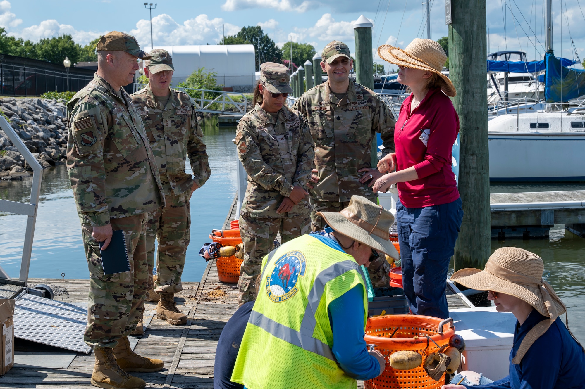 U.S. Air Force Col. James M. Clark, far left, commander of Joint Base Anacostia-Bolling and the 11th Wing, and Jennifer McDonnell, far right, installation management flight chief with the 11th Civil Engineer Squadron, discuss environmental benefits during the young mussel release event on JBAB, Washington, D.C., Aug. 22, 2025. The 11th CES partnered with the National Fish and Wildlife Foundation and the Anacostia Watershed Society to release the mussels, which help clean the water by filtering excess nutrient pollutants. Located at the confluence of the Potomac and Anacostia Rivers, which empty into the Chesapeake Bay watershed, JBAB provides an ideal location for the release initiative. (U.S. Air Force photo by Hayden Hallman)