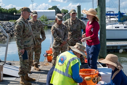 U.S. Air Force Col. James M. Clark, far left, commander of Joint Base Anacostia-Bolling and the 11th Wing, and Jennifer McDonnell, far right, installation management flight chief with the 11th Civil Engineer Squadron, discuss environmental benefits during the young mussel release event on JBAB, Washington, D.C., Aug. 22, 2025. The 11th CES partnered with the National Fish and Wildlife Foundation and the Anacostia Watershed Society to release the mussels, which help clean the water by filtering excess nutrient pollutants. Located at the confluence of the Potomac and Anacostia Rivers, which empty into the Chesapeake Bay watershed, JBAB provides an ideal location for the release initiative. (U.S. Air Force photo by Hayden Hallman)